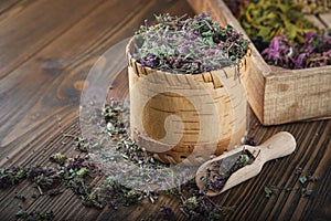 Wooden bowl of dry wild Marjoram or Origanum vulgare plants, wooden crate of medicinal herbs.