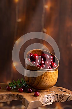 Wooden bowl filled with fresh, ripe red cherries atop a rustic wooden table