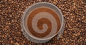 wooden bowl full of grinded coffee on a rotating background of fresh roasted coffee beans