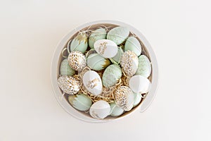 Wooden bowl with golden Easter eggs on white background. Easter celebration concept. Flat lay. Top view