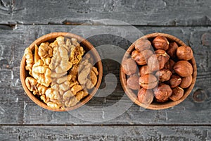 Wooden bowl with hazelnuts and wallnuts on a rustic table. The view from the top