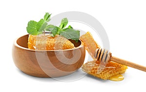 Wooden bowl with honeycomb, dipper and mint on white background