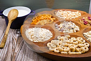 Wooden bowl with mixed breakfast cereals and blue bowl with fresh milk