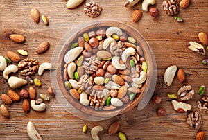 Wooden bowl with mixed nuts on rustic table top view. Healthy food and snack