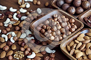 Wooden bowl with mixed nuts on table top view. Healthy food and snack. Walnut, pistachios, almonds, hazelnuts and