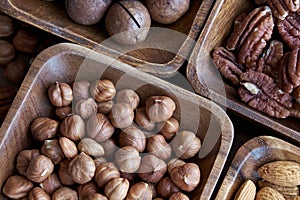 Wooden bowl with mixed nuts on table top view. Healthy food and snack. Walnut, pistachios, almonds, hazelnuts and