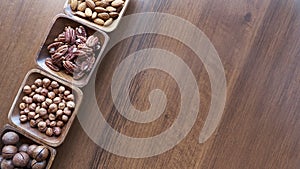 Wooden bowl with mixed nuts on table top view. Healthy food and snack. Walnut, pistachios, almonds, hazelnuts and