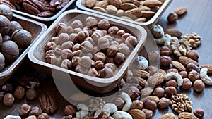 Wooden bowl with mixed nuts on table top view. Healthy food and snack. Walnut, pistachios, almonds, hazelnuts and