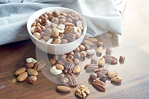 Wooden bowl with mixed nuts on table top view. Healthy food and snack. Walnut, pistachios, almonds, hazelnuts and