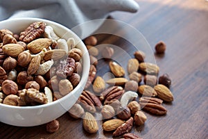 Wooden bowl with mixed nuts on table top view. Healthy food and snack. Walnut, pistachios, almonds, hazelnuts and