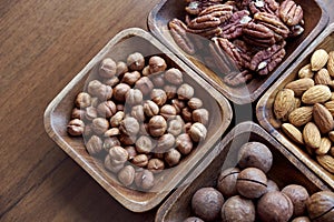 Wooden bowl with mixed nuts on table top view. Healthy food and snack. Walnut, pistachios, almonds, hazelnuts and