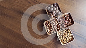 Wooden bowl with mixed nuts on table top view. Healthy food and snack. Walnut, pistachios, almonds, hazelnuts and