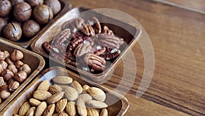 Wooden bowl with mixed nuts on table top view. Healthy food and snack. Walnut, pistachios, almonds, hazelnuts and