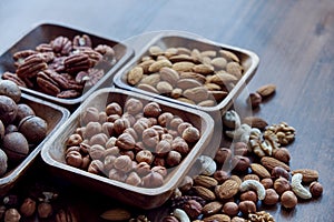 Wooden bowl with mixed nuts on table top view. Healthy food and snack. Walnut, pistachios, almonds, hazelnuts and