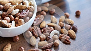 Wooden bowl with mixed nuts on table top view. Healthy food and snack. Walnut, pistachios, almonds, hazelnuts and