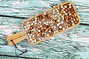 Wooden bowl with mixed nuts on white table top view. Healthy food and snack. Walnut, pistachios, almonds, hazelnuts