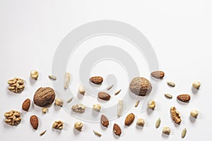 Wooden bowl with mixed nuts on white table top view. Healthy food and snack. Walnut, pistachios, almonds, hazelnuts