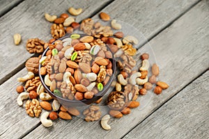 Wooden bowl with mixed nuts on a wooden gray background. Walnut, pistachios, almonds, hazelnuts and cashews, walnut