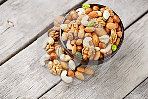 Wooden bowl with mixed nuts on a wooden gray background. Walnut, pistachios, almonds, hazelnuts and cashews, walnut