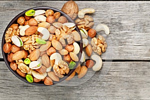 Wooden bowl with mixed nuts on a wooden gray background. Walnut, pistachios, almonds, hazelnuts and cashews, walnut