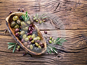 The wooden bowl with olive berries on the table.