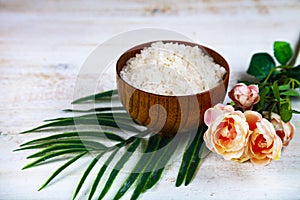 Wooden bowl with sea salt, rose and palm leaf