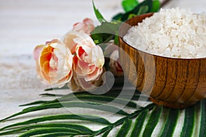 Wooden bowl with sea salt, rose and palm leaf