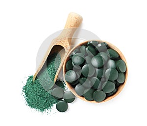 Wooden bowl of spirulina pills and powder in scoop on white background