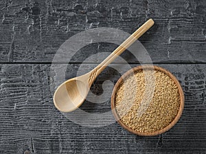 Wooden bowl and spoon with amaranth seeds on dark wooden table. Gluten free food.