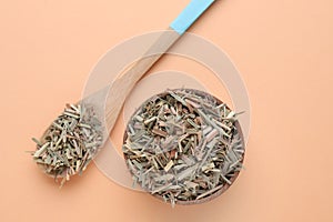 Wooden bowl and spoon with aromatic dried lemongrass on beige background, flat lay