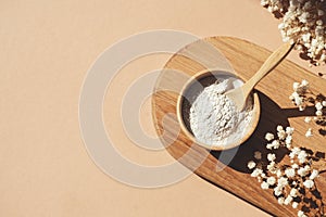 Wooden bowl with a spoon filled with white bath sea salt. Beauty treatment for spa and wellness on beige background.