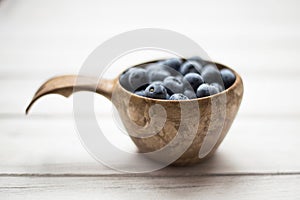 Wooden bowl with summer blueberries close up