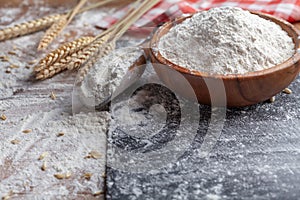 Wooden bowl of wheat flour and scoop on kitchen table. Ingredient for baking