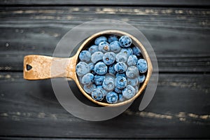 Wooden bowl withsweet blueberries on black table