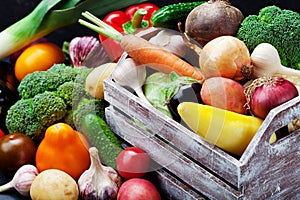 Wooden box with autumn harvest farm vegetables and root crops. Healthy and organic food background.