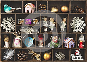 A wooden box with cells filled with small Christmas and New Year decor.