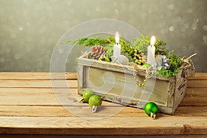 Wooden box with Christmas decorations and candles over dreamy background. Christmas table composition