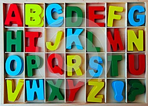 Wooden box of colorful wood english letters. front view. Letters and signs for DIY. letters in frame. close up image. colourful