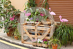Wooden box, decorated with some pink flamingos and flower pots on \