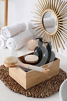 Wooden box with different toiletries and brush on countertop in bathroom