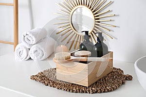 Wooden box with different toiletries and brush on countertop in bathroom