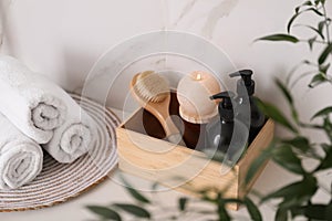 Wooden box with different toiletries, burning candle and clean towels on countertop in bathroom