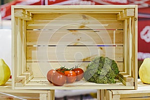 Wooden box almost empty, with only two tomatoes and a broccoli