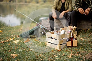 Wooden box with firewoods and bottles with alcoholic beverages at picnic