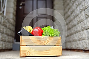 Wooden box with food shopping near door during coronavirus quarantine. Customer receiving online order at home. Food delivery