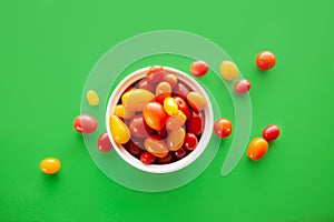 Wooden box with fresh cherry tomatoes. Red, orange and yellow cherry tomatoes on green background