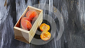 Wooden box with fresh sweet peaches on a dark background. Seasonal harvest crop local produce concept. Flat lay. Copy space