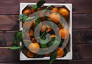 Wooden box of fresh tangerines with leaves. View from top