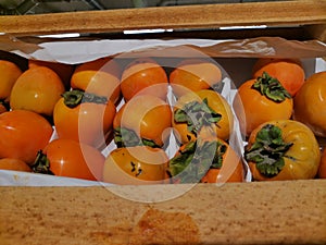 A wooden box of fresh tasty organic persimmons