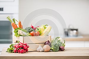 Wooden box full of fresh healthy vegetables. Broccoli carrot radish onion garlic corn on wooden kitchen table